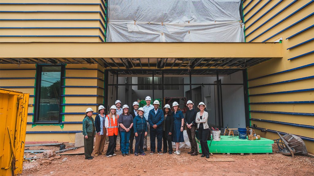 A group of people stand in front of a building under construction.
